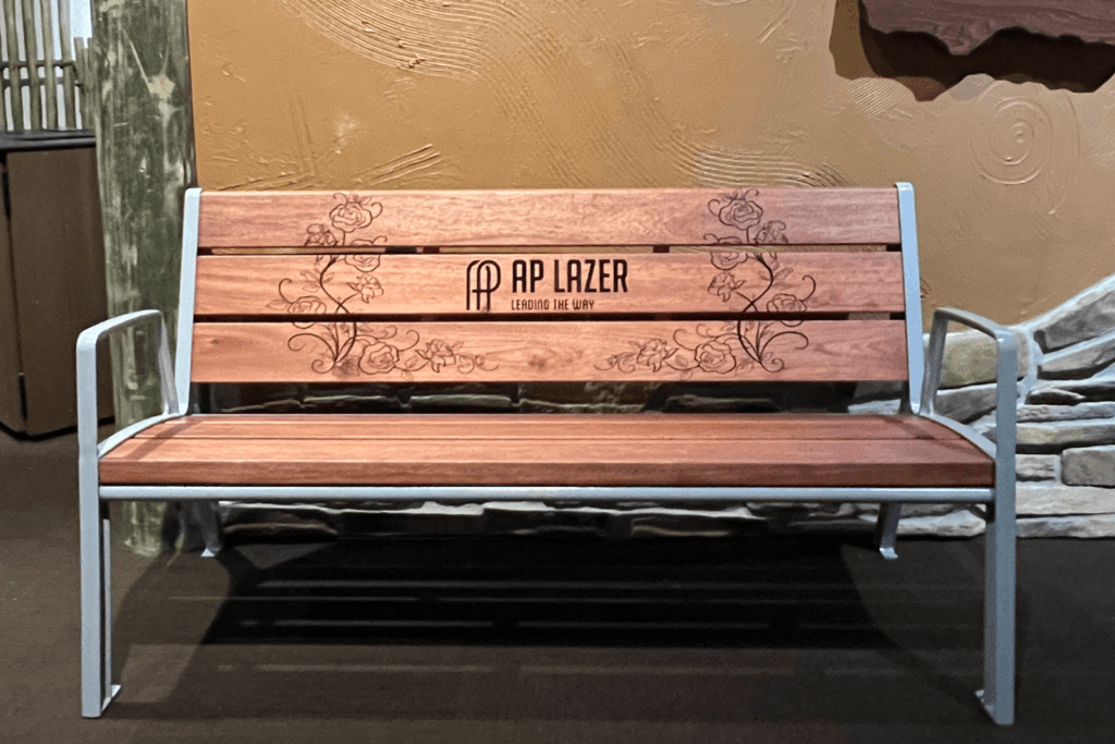 A Laser-Engraved Branding Bench With The Ap Lazer® Logo Is Set In A Convention Hallway.