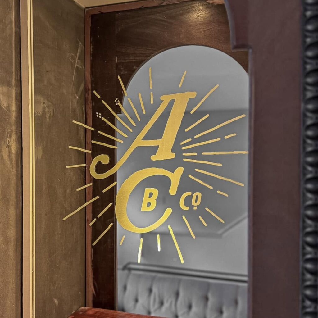 A laser engraved logo on a glass mirror, paint filled with gold paint.