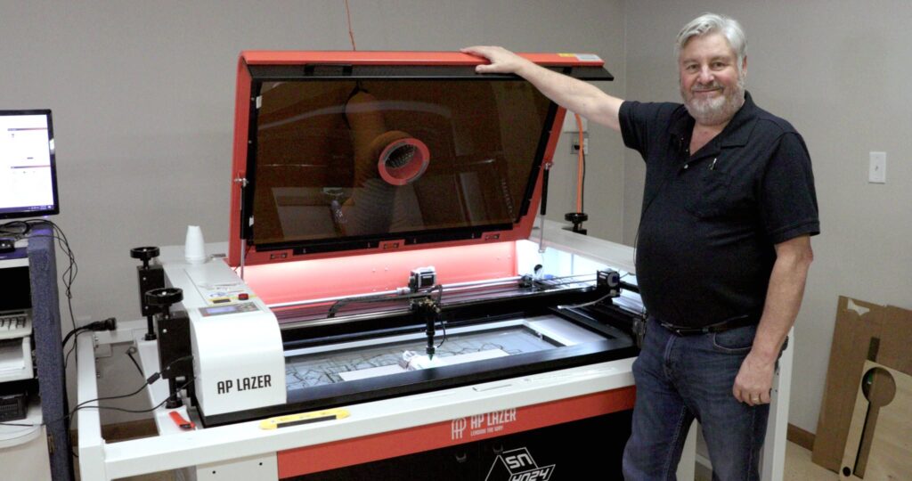 A photo of AP Lazer customer, business owner, and family member, Jeff Nelson of Bolt Laserworks, standing with his SN4024 AP Lazer machine.