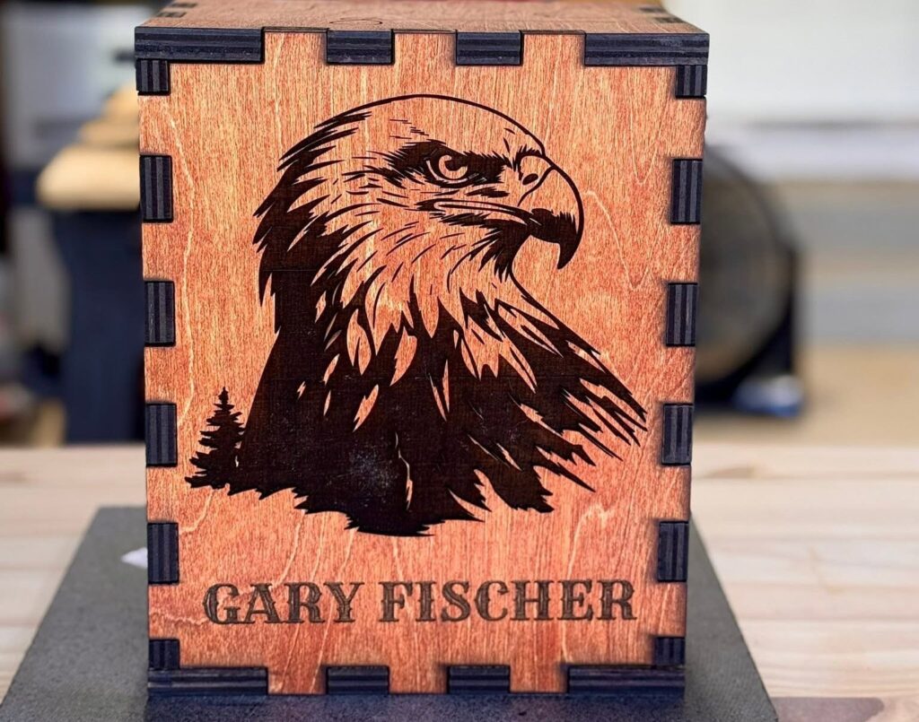 A photo of a laser engraved and cut wooden puzzle box urn with an eagle on it.